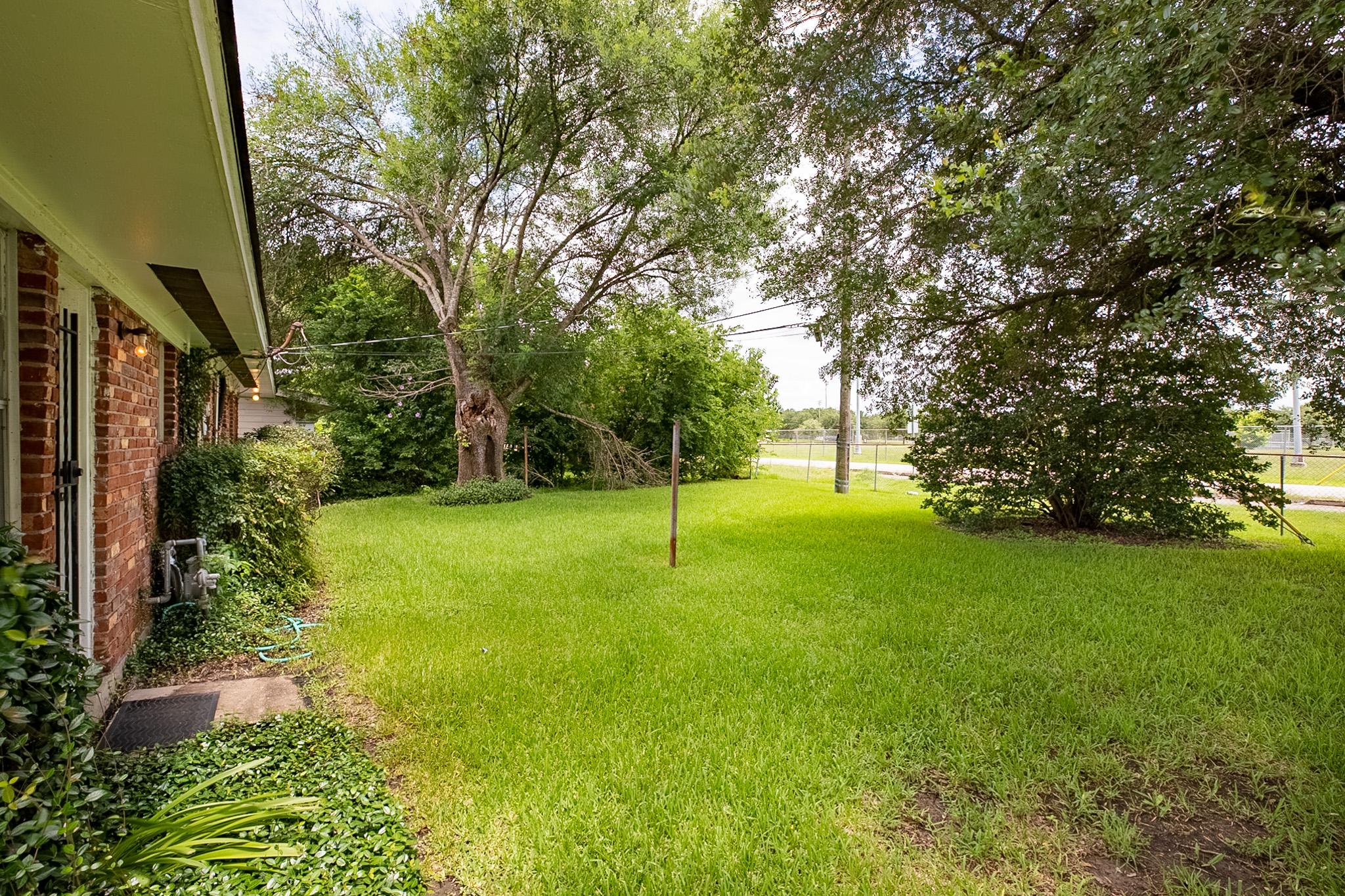 Real estate photography of residential home's backyard area with grass patches missing.